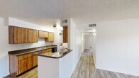 Located at 5959 North 78th Street in Scottsdale, Arizona, this single-floor, 2-bedroom, 2-bathroom residence offers a practical and well-organized layout. Wood-look flooring runs consistently throughout the home, complementing the neutral white walls and textured ceilings found in most rooms.

The galley-style kitchen is efficiently designed with warm wood cabinetry lining both walls, dark countertops, a double-basin sink, and black appliances including a range and refrigerator. A peninsula with matching countertop extends into the adjacent dining area, creating a natural transition between the two spaces. A hallway off the kitchen connects the living areas to the rest of the home.

The living room is bright and open, featuring French doors that invite natural light and provide outdoor access. A secondary bedroom also benefits from natural light through a window with blinds. The primary bedroom is a comfortable size and connects to a hallway with built-in wood cabinetry for additional storage.

Both bathrooms are functional in design, each featuring wood vanities with dark countertops, large mirrors, and tub-shower combinations with clean white surrounds. The overall layout is straightforward and efficient, making effective use of the available space throughout the home.