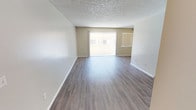 This single-floor residence offers a well-organized layout with a clean, neutral aesthetic throughout. The open living area is finished with durable hardwood-style flooring and features a textured ceiling, crisp white baseboards, and a large sliding glass door fitted with vertical blinds that fills the space with natural light and provides outdoor views. The generous proportions of the living room make it an inviting and versatile area.

The kitchen is designed in a galley configuration, featuring white cabinetry, granite-style countertops, a stainless steel sink, and a gas range with a built-in microwave, all complemented by hardwood-style flooring and a bright overhead light fixture.

The bedrooms are carpeted for comfort and warmth, each with vertical-blind-covered windows that admit soft, diffused natural light. The primary bedroom includes a spacious walk-in closet and direct access to an en-suite bathroom. Both bathrooms are appointed with granite-topped vanities, large mirrors with lighted fixtures, and a shower-tub combination, offering a functional and consistent finish throughout.

Overall, the unit presents a cohesive, neutral color palette of warm beige and gray tones, creating a calm and practical living environment suitable for a variety of occupants.