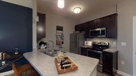 Located at 5260 Franklin St in Hilliard, Ohio, this single-floor residence offers a thoughtfully designed layout with a warm, eclectic character throughout. The kitchen is a functional highlight, featuring dark espresso cabinetry, light stone-look countertops, stainless steel appliances including a refrigerator, electric range, and built-in microwave, as well as wood-look luxury vinyl plank flooring. A peninsula with a double sink provides additional prep space and adds an open, connected feel. Conveniently tucked just off the kitchen is an in-unit laundry area with a full-size washer and dryer. The living room makes a bold statement with deep navy accent walls, hardwood-style flooring, and large windows that invite natural light. It offers generous space for seating and entertainment. The bedrooms are carpeted and comfortably sized, each with its own distinct character — one features a rustic barn door headboard detail, while another benefits from a bright window with pleasant outdoor views. The full bathroom is finished with vinyl plank flooring, a dark vanity with a single sink, and a shower-tub combination. Overall, the space blends modern finishes with warm, rustic accents to create an inviting and functional home.