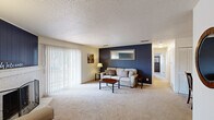 Located at 2900 Middle Rd in Bettendorf, Iowa, this 2-bedroom, 2-bathroom single-floor residence offers a thoughtfully arranged layout with comfortable living spaces throughout. The living room is a standout area, featuring a classic brick fireplace with a bold navy accent wall and sliding glass doors that open to a private outdoor balcony, allowing natural light to flow in. An adjacent sitting area provides additional flexible living space. The combined dining and living area is finished with plush carpeting and a ceiling fan, with louvered bi-fold closet doors adding a distinctive architectural touch. The kitchen is a well-organized galley-style space with warm oak cabinetry, ample counter space, a stainless steel sink, and tile flooring — offering practical storage and functionality. The primary bedroom is generously sized, featuring dual windows with outdoor views and soft carpeting. The second bedroom is equally comfortable, also with a window and natural light. Both bathrooms are clean and functional, with tile flooring and warm wood vanities. Throughout the home, textured ceilings and neutral tones create a cohesive, understated aesthetic that complements the overall livable and welcoming character of the space.