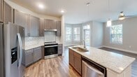 This well-appointed single-story home in Charlotte, NC offers 2 bedrooms, 3 bathrooms, and 2 closets within a comfortable, thoughtfully designed layout. The open-concept kitchen serves as a centerpiece, boasting granite countertops, a large island with an undermount sink and pendant lighting, grey shaker-style cabinetry, a subway tile backsplash, stainless steel appliances, and a bay window that floods the space with natural light. Wood-look flooring runs throughout the main living areas, creating a cohesive and clean aesthetic. The primary bedroom features plush carpeting, a ceiling fan, and direct access to an en suite bathroom with a dual-sink granite vanity, dark wood cabinetry, and an adjacent walk-in closet equipped with wire shelving systems for organized storage. The second bedroom is carpeted and bright, with dual windows offering outdoor views. The bathrooms are finished with granite vanities and wood-look flooring; one bathroom is notably ADA-accessible, featuring multiple stainless steel grab bars for enhanced safety and convenience. A second walk-in closet with wire shelving adds further storage capacity. The neutral color palette and modern finishes throughout create a clean, functional, and welcoming atmosphere.