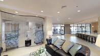 Located at 260 Leigh Farm Rd in Durham, NC, this sophisticated single-floor amenity space combines upscale design with a broad range of functional areas. The layout flows seamlessly from one zone to the next, beginning with an inviting lounge featuring a tufted leather sofa, a striking curved decorative screen, and recessed lighting set against neutral tones — all with direct sightlines into the fitness center beyond, enclosed by sleek steel-framed glass partitions.

The fitness center is fully equipped with cardio and strength-training machines, bathed in natural light from floor-to-ceiling windows. Adjacent to it, a well-appointed kitchen features white cabinetry, quartz countertops, pendant lighting, stainless steel appliances, and a built-in coffee station — ideal for resident or community use.

A casual dining area offers round white tables and cross-back chairs arranged beneath recessed lighting, with a wall-mounted fireplace and television providing a warm focal point. A separate sitting room with large windows overlooks an outdoor courtyard, filling the space with natural light and exterior views.

Completing the layout is a private conference room with a wood table, upholstered chairs, a designer pendant fixture, and textured wallcovering — suited for meetings or private gatherings. Throughout, large-format tile flooring, tray ceilings, and refined finishes create a cohesive, polished atmosphere.