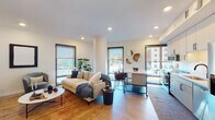 This single-floor residence showcases a contemporary design with clean lines, neutral tones, and light wood flooring throughout. The open-concept living area is bathed in natural light from large, floor-to-ceiling windows with roller shades, offering views of the surrounding cityscape. The living space comfortably accommodates both a lounge area and a dining nook, anchored by recessed lighting and smooth white ceilings.

The kitchen features light grey cabinetry, white quartz countertops, a classic subway tile backsplash, and a full suite of stainless steel appliances, including a refrigerator with ice maker, dishwasher, and range with microwave. A kitchen island provides additional prep and dining space.

A well-lit hallway connects the bedrooms and bathrooms, lined with framed artwork and closets with louvered doors. The bedrooms are calm and versatile, each offering light-filled windows, ample storage, and space for a desk or media setup. Two full bathrooms feature white tile, tub-shower combinations, wide vanity mirrors, and dual sinks in the larger bath, maintaining the unit's clean, modern aesthetic throughout.