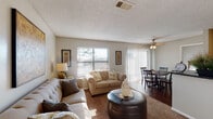 This single-story, one-bedroom, one-bathroom residence in Little Rock, Arkansas, offers a comfortable and efficiently designed layout. The living area is spacious enough to accommodate multiple seating arrangements and features a textured ceiling, carpet flooring, and windows fitted with horizontal blinds that allow natural light to filter throughout the space. The living area flows seamlessly into the dining space, which is highlighted by a ceiling fan with a light fixture and a sliding glass door with vertical blinds that invites additional natural light.

The kitchen is functional and compact, featuring dark countertops, wood-toned cabinetry, and black appliances including a refrigerator, electric range, and built-in microwave. Notably, an in-unit stacked washer and dryer is conveniently tucked within the kitchen area, adding practical value. Wood-style flooring runs through the kitchen and dining area, providing a contrast to the carpeted living and bedroom spaces.

The bedroom is a comfortable, naturally lit retreat with carpet flooring and a window with blinds. It opens directly into the main living space, creating an accessible flow between rooms. The bathroom includes a tub-shower combination with tile surround and wood-style flooring, completing this well-organized residence.