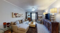 This single-floor, 2-bedroom, 2-bathroom residence offers a well-organized layout with modern finishes and a warm, cohesive aesthetic. The living room is a comfortable, carpeted space featuring crown molding, a ceiling fan, and a window that allows natural light to fill the room. It flows seamlessly into the dining area, which is accented by a stylish pendant light, decorative mirrors, and wood-look flooring that extends into the kitchen. The kitchen is equipped with dark espresso cabinetry, granite-style countertops, stainless steel appliances including an electric range and refrigerator, and a separate pantry for added storage. Both bathrooms mirror each other in design, each featuring dark vanity cabinetry, granite-style countertops, a tub-shower combination, a large mirror, and wood-look flooring. The two bedrooms are generously sized and carpeted, each with a ceiling fan and window treatments providing privacy. The primary bedroom offers a quiet, well-proportioned retreat, while the second bedroom includes ample natural light. Throughout the residence, neutral wall tones, crown molding in the main living areas, and consistent finishes create a unified and polished interior environment.