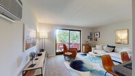 Located in West Chester, PA, this one-bedroom, one-bathroom residence offers a well-designed single-floor layout that makes efficient use of its intimate footprint. The living room serves as the heart of the home, filled with natural light streaming through large sliding glass doors that open onto a private balcony overlooking mature, leafy trees — creating a serene, nature-connected atmosphere. The living space is comfortable and versatile, with room for both lounging and entertaining. Adjacent to the living area, the kitchen features warm oak cabinetry, white appliances, hardwood-style flooring, and a granite-topped breakfast bar with seating — ideal for casual dining. The spacious primary bedroom is a restful retreat, highlighted by a ceiling fan, a bold accent wall, and access to a dedicated walk-in closet. A window allows natural light to brighten the room. The full bathroom is clean and straightforward, finished with tile flooring and a white vanity. Throughout the residence, a neutral color palette and consistent finishes create a cohesive, move-in-ready aesthetic. The private balcony, surrounded by greenery, adds a peaceful outdoor escape to this well-appointed West Chester home.