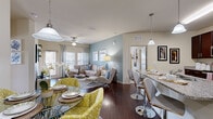 Located at 5400 Coraci Blvd in Port Orange, Florida, this well-appointed 2-bedroom, 1-bathroom single-story residence offers a thoughtfully designed open-concept layout. Rich hardwood-style flooring flows throughout the main living area, connecting the kitchen, dining, and living spaces seamlessly. The kitchen is outfitted with dark espresso cabinetry, granite countertops, stainless steel appliances, and a breakfast bar with pendant lighting — ideal for both casual dining and entertaining. The living room features a soothing blue-grey accent wall, ceiling fan, and large windows that invite natural light. The primary bedroom is generously sized, complete with plush carpet, neutral tones, a decorative accent wall, and a spacious walk-in closet with built-in shelving. The second bedroom also features carpet, natural light, and ample space. The full bathroom includes a granite-topped double vanity with rich wood cabinetry, a tiled tub-shower combination, and tile flooring. A dedicated in-unit laundry area with full-size washer and dryer adds everyday convenience. Two closets provide abundant storage throughout this well-rounded residence.