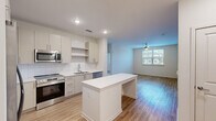 Located at 2720 Bristlecone Trail in Raleigh, NC, this well-designed 2-bedroom, 2-bathroom home offers a clean, modern aesthetic across a single floor. The open-concept layout seamlessly connects the kitchen and living room, creating a bright and functional shared space. The kitchen is appointed with white flat-front cabinetry, a subway tile backsplash, stainless steel appliances including a range, microwave, dishwasher, and French door refrigerator, and a central island with a white countertop that provides additional prep and dining space. The living area benefits from natural light through a window and is equipped with a ceiling fan. Light wood-tone flooring runs consistently throughout the home, lending warmth and continuity to every room. Both bedrooms are comfortably sized, each featuring ceiling fans and generous closet space — including walk-in closets outfitted with wire shelving systems for organized storage. The primary bedroom offers direct access to both a walk-in closet and a dedicated bathroom. The primary bathroom includes a dual-sink vanity with a large mirror, wood-tone cabinetry, and a full soaking tub with tiled surround. The second bathroom maintains the same crisp, contemporary style. With three total closets and a thoughtful layout, this home delivers practical, comfortable living in Raleigh.