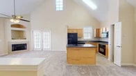 Located at 5900 SW 76th Court in Gainesville, FL, this multi-story home spans three floors and offers a thoughtfully designed layout with two bedrooms, two bathrooms, and a versatile loft space. The main floor is the heart of the home, showcasing a dramatic vaulted ceiling that rises to an impressive height, flooding the open-concept kitchen and living area with natural light through a skylight and high clerestory windows. The kitchen features warm honey-toned cabinetry, dark granite countertops, a center island, and black appliances, including a French door refrigerator and built-in oven. The living area is anchored by a cozy fireplace with a built-in display nook above, a ceiling fan, and French doors that open to the outdoors. The main floor also includes a hallway and convenient access to the stairways. Upstairs, the loft offers flexible additional living space with a large window and staircase access. The bedrooms are carpeted and feature ceiling fans and walk-in closets with wire shelving. The bathrooms are finished with tile flooring. Throughout the home, neutral tones, plush carpeting, and an abundance of natural light create a warm and welcoming ambiance.