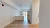 This thoughtfully designed studio in Stevensville, MD offers an efficient and modern single-floor layout. The open main living area features light-toned hardwood-style flooring, crisp white walls, and clean-lined trim throughout, creating a bright and airy atmosphere. A half-wall partition adds subtle definition to the living space without compromising the open feel, while a sliding glass door leads to a private balcony, inviting natural light and outdoor views into the interior.

The kitchen is well-appointed with white shaker-style cabinetry, a grey subway tile backsplash, light countertops, and a full suite of stainless steel appliances including a range, microwave, dishwasher, and refrigerator — offering both style and functionality in a compact footprint.

A dedicated walk-in closet provides generous storage with wire shelving systems lining the walls, complemented by the same hardwood-style flooring found throughout the unit. The bathroom is finished with large-format grey stone-look tile on both the floors and shower surround, paired with a soaking tub and clean white walls for a calm, spa-like feel. Safety grab bars are also thoughtfully incorporated. The entrance offers a welcoming transition into the space, completing this efficiently planned studio.