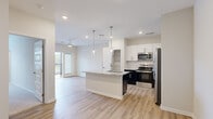 Located at 3025 Headwater Dr in Southport, NC, this well-appointed single-story home offers three bedrooms, two bathrooms, and a thoughtfully designed open-concept floor plan. The kitchen is a standout feature, showcasing two-tone cabinetry with white upper cabinets and deep navy lower cabinets, granite countertops, a subway tile backsplash, and a full suite of stainless steel appliances. A central island with a granite surface and pendant lighting above serves as both a prep area and a natural gathering point that flows into the living area, which includes a ceiling fan and access to an outdoor balcony. The primary bedroom is generously sized, featuring plush carpet flooring, a ceiling fan, and sliding glass door access to the balcony. Additional bedrooms are carpeted with ceiling fans and bright windows that allow ample natural light. The primary bathroom includes a sleek walk-in shower with frameless glass doors and built-in shelving, while the secondary bathroom offers a tub-shower combo with a dark vanity and granite countertop. Throughout the living areas, durable light-toned wood-look flooring adds a clean, cohesive aesthetic. A dedicated laundry room houses a full-size washer and dryer with overhead wire shelving, adding practical convenience to this move-in-ready home.