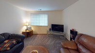 Located at 11200 W Cleveland Ave in West Allis, Wisconsin, this single-floor unit offers a well-organized layout designed for comfortable everyday living. The living room is generously sized, featuring neutral carpet flooring, large windows with blinds that bring in natural light, and an open sightline into the dining area, which is finished with a ceiling fan overhead. The galley-style kitchen is efficiently laid out with wood-toned cabinetry, dark laminate countertops, tile flooring, a double basin sink, and black appliances including a refrigerator and range. The unit includes two bedrooms. The primary bedroom features sliding glass doors with vertical blinds opening to an outdoor space with greenery views, along with carpeted flooring and ample room for a dresser and media setup. The second bedroom is bright and cozy, with a window dressed in sheer curtains and blinds, soft carpet, and generous closet access. Two bathrooms serve the unit — one with a wide vanity, large mirror, and bright vanity lighting, and a second full bathroom with a wood-cabinet vanity, tile flooring, and a shower-tub combination. Throughout the unit, neutral wall tones and consistent carpet and tile flooring create a cohesive, move-in ready environment.