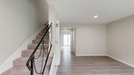 This two-story, 2-bedroom, 2-bathroom home in Azusa, California offers a functional and well-appointed layout spread across two floors. The main level features a bright, open living room with light-toned hardwood-style flooring, recessed lighting, and a seamless flow toward the combined dining area and kitchen. The kitchen is outfitted with white cabinetry, granite-style countertops, stainless steel appliances including a gas range and refrigerator, and tile flooring. A sliding glass door leads directly to a private outdoor patio, allowing natural light to fill the space. A convenient half bathroom with a granite-topped vanity is also located on the main floor. A carpeted staircase with a sleek black metal railing connects the two levels. Upstairs, both bedrooms feature plush carpet, ceiling fans, and windows with vertical blinds that filter in natural light. Three closets provide ample storage throughout. The full upstairs bathroom includes a granite vanity, tub-shower combo, and hardwood-style tile flooring. An in-unit laundry area adds everyday convenience. The home's neutral color palette and clean finishes create a bright, move-in-ready atmosphere throughout.