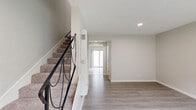 This two-story, 2-bedroom, 2-bathroom home in Azusa, California offers a functional and well-appointed layout spread across two floors. The main level features a bright, open living room with light-toned hardwood-style flooring, recessed lighting, and a seamless flow toward the combined dining area and kitchen. The kitchen is outfitted with white cabinetry, granite-style countertops, stainless steel appliances including a gas range and refrigerator, and tile flooring. A sliding glass door leads directly to a private outdoor patio, allowing natural light to fill the space. A convenient half bathroom with a granite-topped vanity is also located on the main floor. A carpeted staircase with a sleek black metal railing connects the two levels. Upstairs, both bedrooms feature plush carpet, ceiling fans, and windows with vertical blinds that filter in natural light. Three closets provide ample storage throughout. The full upstairs bathroom includes a granite vanity, tub-shower combo, and hardwood-style tile flooring. An in-unit laundry area adds everyday convenience. The home's neutral color palette and clean finishes create a bright, move-in-ready atmosphere throughout.