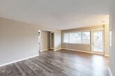 Located at 4820 Kenmore Ave in Alexandria, Virginia, this well-appointed single-floor residence offers three bedrooms, two bathrooms, and a thoughtfully designed layout that maximizes comfort and functionality. The open living room greets you with warm wood-style plank flooring, neutral warm-toned walls, and a large picture window that fills the space with natural light and provides outdoor views. A separate dining room flows seamlessly from the living area, supported by connecting hallways that guide you through the home. The galley-style kitchen is a standout feature, boasting crisp white shaker cabinetry extending to the ceiling, gray quartz-style countertops, a subway tile backsplash, and a full suite of stainless steel appliances including a range, microwave, refrigerator, and dishwasher. The generous primary bedroom is carpeted for comfort, includes a wall-mounted climate control unit, and receives natural light through a double-hung window. Two additional bedrooms and three closets offer ample storage throughout. The bathrooms are finished with clean white subway tile surrounding a soaking tub with brushed gold fixtures. A dedicated laundry area adds everyday convenience to this move-in-ready home.