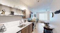 Located at 340 Legion Dr in Lexington, Kentucky, this efficiently designed one-bedroom, one-bathroom residence makes smart use of its space through an open, modern layout. Light wood-toned flooring runs throughout, lending warmth and continuity across the unit.

The kitchen is thoughtfully appointed with warm wood cabinetry, white quartz countertops, a stainless steel single-basin sink, and a full suite of stainless steel appliances including a refrigerator, electric range with microwave above, and dishwasher. Open metal shelving above the counter provides additional storage and display space, while the kitchen flows seamlessly into the living area, which features a ceiling fan and a large window that invites natural light.

The bedroom is a calm, well-proportioned retreat with clean white walls, light wood flooring, and a ceiling fan with pendant lighting. A large roller shade window provides soft, diffused light, and the room offers ample space for a full furniture arrangement. A dedicated closet adds practical storage.

The bathroom is clean and contemporary, featuring a walk-in shower with a sliding glass door, a wood-toned vanity with a white countertop, and wood-look flooring that ties the space together. The overall ambiance of the unit is modern, bright, and functional, ideal for comfortable single-occupant living.