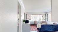 This thoughtfully designed 2-bedroom, 3-bathroom residence offers a single-floor layout that maximizes every square foot. The open living area serves as the heart of the home, featuring warm hardwood flooring and a wall of large windows that frame sweeping urban cityscape views, flooding the space with natural light. A kitchen with white cabinetry and modern fixtures sits adjacent to the living area, creating a seamless flow throughout.

The spacious primary bedroom is a standout feature, offering generous floor space, hardwood floors, large windows with city views, and ample room for a full bedroom suite. The second bedroom is well-sized and functional, complete with a built-in desk area, wall-mounted media panel, and wood flooring.

All three bathrooms are finished in a clean, contemporary style with white subway tile, chrome fixtures, pedestal sinks with chrome frames, and backlit vanity mirrors with glass shelving. Two bathrooms feature walk-in showers, while a third includes a full soaking tub with shower combination, providing flexible options for residents.

Crown molding, textured ceilings, and consistent hardwood flooring throughout tie the space together with a cohesive, urban-residential aesthetic. A central hallway connects all rooms, ensuring an efficient and intuitive flow across the entire residence.