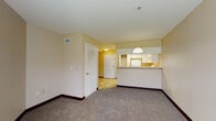 This single-floor unit is thoughtfully laid out to maximize functionality and comfort. The open-concept living area is finished with wall-to-wall carpet and neutral, warm-toned walls, creating a welcoming atmosphere. A raised breakfast bar visually separates the living space from the kitchen, which is illuminated by a pendant light overhead. The kitchen is outfitted with white cabinetry providing generous storage, light-toned countertops, a full-size refrigerator, and an electric range with an overhead ventilation hood. Tile flooring runs throughout the kitchen and entry areas, offering a practical contrast to the carpeted living and sleeping spaces.

The unit includes spacious bedrooms, each carpeted and featuring neutral walls with dark baseboards. One bedroom benefits from a large window that invites natural light and offers a view of greenery outside. Both bedrooms provide access to closet space and connect conveniently to the hallway. The bathroom includes a full soaking tub with a tub surround, a toilet, and a vanity with a white countertop, all set on tile flooring. Throughout the unit, the overall ambiance is clean, functional, and move-in ready.