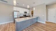 This two-story residence in Papillion, Nebraska offers a modern and functional layout across two levels. The main living area is anchored by an open-concept kitchen and living room featuring warm wood-look flooring, recessed lighting, and large windows that flood the space with natural light. The kitchen stands out with a generous granite-topped island, sleek two-tone cabinetry in white and dark wood, stainless steel appliances, and elegant pendant lighting — ideal for both everyday living and entertaining.

Both bedrooms are carpeted and bathed in natural light from oversized windows with outdoor neighborhood views, each equipped with a ceiling fan for added comfort. The bedrooms are complemented by two walk-in closets outfitted with built-in shelving and hanging rods, providing ample storage. The two bathrooms are finished with granite countertops, dark wood vanities, and full tub-shower combinations set on wood-look tile flooring.

A dedicated laundry room with a full-size washer and dryer adds everyday convenience. Neutral warm-toned walls and consistent flooring choices throughout create a cohesive, move-in ready aesthetic. Two staircases connect the levels, enhancing accessibility and flow throughout this well-designed home.