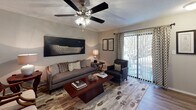 This single-story residence in Garden City, Georgia offers a thoughtfully arranged floor plan with multiple bedrooms, a well-appointed kitchen, a dedicated dining area, a comfortable living room, and two full bathrooms. The layout flows naturally from one space to the next, creating a cohesive and functional living environment.

The living room serves as a central gathering space, featuring wood-look flooring, a ceiling fan with integrated lighting, and a sliding glass door that invites natural light and provides direct access to an outdoor patio area. The kitchen is outfitted with dark shaker-style cabinetry, granite-look countertops, a double-basin sink, and black appliances. A convenient pass-through to a laundry closet with built-in shelving adds practical utility to the space. Adjacent to the kitchen, the dining area accommodates a round table and chairs beneath a textured ceiling, with wainscoting detail along the lower walls.

The bedrooms are carpeted and each includes a ceiling fan, offering a restful atmosphere. The two full bathrooms feature tub-shower combinations, granite-look vanity tops, wood-look flooring, and neutral wall tones. Throughout the unit, a consistent coastal-inspired design aesthetic ties the spaces together, creating a warm and inviting overall ambiance.