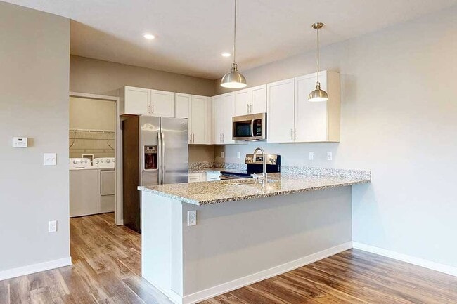 Cook, dine, and gather with ease in this modern kitchen featuring granite countertops, stainless steel appliances, and a spacious breakfast bar. - The Villas at Falling Waters