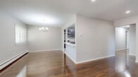 Located at 143 West Farrell Avenue in Ewing Township, NJ, this two-bedroom, one-bathroom residence offers a thoughtfully organized single-floor layout with a clean, modern aesthetic throughout. Rich, dark hardwood floors run through the living areas, hallway, and bedrooms, lending warmth and continuity to the space.

The open living and dining area is bright and welcoming, featuring recessed lighting and a classic chandelier above the dining space. A pass-through opening connects seamlessly to the kitchen, which is appointed with dark gray shaker-style cabinetry, white quartz countertops, a subway tile backsplash, and stainless steel appliances including a range, microwave, and refrigerator. Light-toned tile flooring completes the kitchen's contemporary look.

The spacious primary bedroom offers generous proportions, a sliding closet, and access to additional rooms. The second bedroom is well-sized and also includes a closet. A central hallway with an additional closet connects all areas efficiently. In total, the unit provides three closets for ample storage.

The bathroom is elegantly finished with a white vanity, tile flooring, and a tub-shower combination dressed in striking marble-look surround panels. A dedicated laundry area adds everyday convenience. Neutral gray walls and consistent finishes throughout create a cohesive, move-in-ready environment.