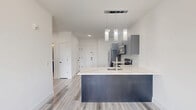 This thoughtfully designed one-bedroom, one-bathroom unit at 69 William St in Belleville, NJ offers a clean, modern aesthetic throughout. Light wood-style flooring flows seamlessly across the entire space, complementing the crisp white walls and creating a bright, cohesive atmosphere.

The kitchen is a standout feature, showcasing two-tone cabinetry with dark lower cabinets and gray upper cabinets paired with white countertops. A full suite of stainless steel appliances — including a refrigerator, electric range, and microwave — provides a polished, functional workspace. A peninsula with an integrated sink and pendant lighting above adds both style and practicality.

The entryway is open and welcoming, offering closet storage and recessed lighting, with a clear line of sight into the kitchen and living areas. The bedroom receives natural light through a window with outdoor views of greenery, and includes a wall-mounted PTAC unit for individual climate control.

The bathroom is finished to a modern standard, featuring large-format white tile in the shower/tub surround, a rain showerhead with matte black accents, and a sleek dark vanity with a white basin sink topped by a frameless mirror. Tile flooring and bright lighting complete the refined look of this well-appointed unit.
