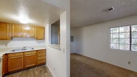 This single-story unit offers a practical and straightforward layout designed for comfortable everyday living. The kitchen is equipped with warm oak cabinetry extending to the ceiling for ample storage, light-toned countertops, a double-basin sink, and a full-size refrigerator. Wood-look vinyl flooring runs throughout the kitchen, providing durability and easy maintenance. A built-in pass-through window connects the kitchen to the adjacent living area, promoting an open feel between the two spaces.

The living area is generously sized, featuring plush wall-to-wall carpeting, neutral white walls, and a textured ceiling. Multiple windows fitted with horizontal blinds allow natural light to filter in, while the front entry door is flanked by a sidelight window, creating a welcoming entryway.

The bedrooms continue the carpeted flooring theme and offer well-proportioned spaces with windows overlooking the outdoors. One bedroom includes a sliding mirrored closet, adding both storage and the illusion of additional space.

The bathroom is clean and functional, outfitted with a single-sink vanity featuring oak cabinetry, a full-size tub-shower combination, and wood-look vinyl flooring that ties in with the kitchen's aesthetic. The textured ceiling is a consistent architectural detail found throughout the unit, contributing to its cohesive design.