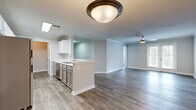 Located at 22 Forest Cir in Newnan, Georgia, this single-floor home offers a thoughtfully designed layout that balances functionality and comfort. Wood-look flooring runs consistently throughout the entire home, providing a clean and cohesive aesthetic from room to room.

The open-concept kitchen is a functional centerpiece, featuring white upper cabinetry, gray lower cabinetry, white countertops, and a full suite of stainless steel appliances including a refrigerator, range, microwave, and dishwasher. A peninsula with an integrated sink adds prep space and connects the kitchen to the adjacent living and dining areas. Ceiling fans in the main living areas promote airflow and comfort.

The bedrooms are well-proportioned, each offering ample natural light through large windows dressed with blinds. Crown molding accents several rooms, adding a polished architectural detail. One bedroom features two doors, suggesting access to a closet and a connecting hallway.

The bathroom is clean and functional, with a single-sink vanity with white cabinetry, a tub-shower combination with tiled surround, and wood-look flooring. A dedicated laundry room provides added convenience, equipped with a full-size washer and dryer alongside overhead wire shelving for storage. The overall palette of soft grays and whites creates a bright, neutral atmosphere throughout.