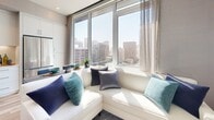This 390-square-foot apartment in downtown San Diego exemplifies efficient urban living. The single-floor layout comprises a living room, bedroom, and bathroom, maximizing space utilization. The living area boasts floor-to-ceiling windows offering stunning city views, filling the space with natural light. A white L-shaped sofa provides comfortable seating and complements the room's modern aesthetic.

The kitchen, while compact, features sleek cabinetry and stainless steel appliances, ensuring functionality without compromising style. The bedroom, measuring 130 square feet, accommodates a queen-sized bed and is adorned with contemporary decor, including a striking upholstered headboard and coordinated bedding in soothing blue tones.

The bathroom, though small, is thoughtfully designed with a white tub-shower combination, modern fixtures, and a bold teal accent wall, adding a pop of color. Throughout the apartment, warm wood flooring creates a cohesive look and adds warmth to the space.

Artistic touches, such as abstract wall art and carefully placed indoor plants, contribute to the apartment's sophisticated ambiance. The overall design balances form and function, making the most of the limited square footage while maintaining a stylish and inviting atmosphere perfect for contemporary city living.