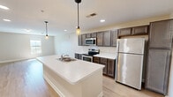 Located in Sevierville, Tennessee, this single-story, 3-bedroom, 2-bathroom home offers a thoughtfully designed layout ideal for comfortable everyday living. The open-concept kitchen and living area serves as the heart of the home, featuring dark-stained cabinetry, light quartz countertops, stainless steel appliances, and a large central island with a built-in sink and pendant lighting overhead. Light-toned hardwood flooring runs throughout the main living areas, creating a bright and cohesive aesthetic. The spacious living room provides generous room for entertaining and flows seamlessly from the kitchen. Each bedroom is carpeted for comfort, with neutral wall tones and windows that invite natural light. The primary bedroom offers a well-proportioned layout, while additional bedrooms feature windows with views of the surrounding landscape. Both bathrooms are finished with dark wood vanities, white countertops, tub-shower combinations, and light hardwood-style flooring. The home maintains a clean, modern aesthetic throughout, with recessed lighting and consistent neutral tones tying each room together. Situated near the amenities of Sevierville and the natural beauty of the Great Smoky Mountains region, this home blends functional design with a welcoming atmosphere.