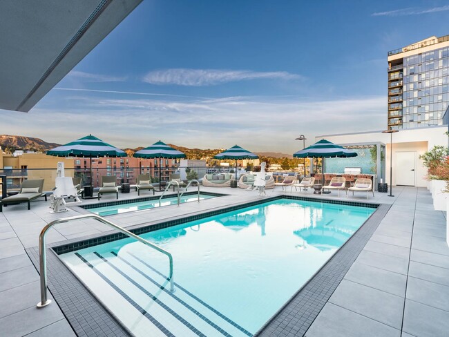 The rooftop pool, designed in a resort-style, features comfortable daybeds and shaded areas for relaxation. - Modera Argyle