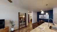 Located at 5151 N 95th Ave in Glendale, Arizona, this single-story residence offers a thoughtfully designed open-concept layout with contemporary finishes throughout. Wood-look flooring flows seamlessly across the main living areas, complemented by crisp white walls and bold teal and navy accent walls that add a modern, curated feel to the space.

The living room is bright and inviting, featuring a ceiling fan, large windows that invite natural light, and direct access to a private outdoor patio. Adjacent to it, the dining area is defined by a rich navy accent wall and pendant lighting, creating an intimate yet open setting.

The kitchen is well-appointed with rich wood-tone cabinetry, stainless steel appliances including a refrigerator, electric range, and microwave, as well as a granite-topped island that doubles as a breakfast bar. Recessed lighting and a white subway tile backsplash round out the polished look.

The bedroom is generously sized with plush carpeting, a ceiling fan, and sliding glass doors opening to the outdoors, filling the room with natural light. A full bathroom features a granite vanity, tub-shower combination, and wood-look flooring.

A dedicated in-unit laundry room with a full-size washer and dryer adds everyday convenience to this well-appointed Glendale residence.