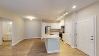 Located at 245 Commons Pkwy in Daleville, Virginia, this single-floor residence offers a thoughtfully designed open-concept layout that seamlessly connects the kitchen, dining, and living areas. The kitchen serves as a central hub, anchored by a granite-topped island with an integrated sink, white shaker-style cabinetry, and a full suite of stainless steel appliances including a refrigerator, range, and microwave. Track lighting overhead provides focused illumination throughout the cooking space, complementing the warm, wood-style hard-surface flooring that extends across the main living areas.

The living room is generously proportioned, featuring a ceiling fan, large windows that allow natural light to fill the space, and access to additional rooms via a set of double doors. Neutral wall tones create a clean, versatile backdrop throughout.

The bedroom offers plush carpeting, a ceiling fan with light fixture, and a large window that brings in natural light. An adjacent walk-in closet provides practical storage with multi-tier wire shelving along the walls. The bathroom includes a tub-shower combination, a white vanity with an integrated sink, a large mirror, and wood-style flooring, finished with brushed nickel hardware for a cohesive, modern aesthetic.