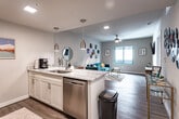 Located at 3200 W Broad St in Richmond, Virginia, this single-floor residence offers a thoughtfully designed layout with a cohesive, modern aesthetic throughout. The living room is a bright and open space, featuring wood-look flooring, a ceiling fan, and a large window that allows natural light to fill the room. The kitchen is a standout feature, equipped with stainless steel appliances including a refrigerator and range, white cabinetry, a subway tile backsplash, and a quartz-topped island with bar seating for two. Sleek pendant lighting anchors the kitchen space, which flows seamlessly into the rest of the unit. The bedroom is a serene retreat, finished with the same warm wood-look flooring, a ceiling fan, and a generous window that brings in natural light. Neutral walls and warm accent lighting create a calm and inviting atmosphere. The bathroom features tile flooring, a vanity with a stone countertop, and a shower-tub combination. Throughout the unit, clean white walls, consistent flooring, and modern finishes contribute to a cohesive and contemporary feel, making this a functional and stylish space in the heart of Richmond.