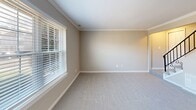 Located at 321 S Amsterdam in Virginia Beach, VA, this two-story home offers a well-organized layout across two equally sized floors. The main level features a bright, modern kitchen-dining area outfitted with crisp white cabinetry, stainless steel appliances including a refrigerator, electric range, microwave, and dishwasher, complemented by light wood-look flooring and a stylish chandelier. A convenient in-unit laundry room sits just off the kitchen. The open living room is finished with plush carpeting and crown molding, with a staircase featuring a classic wrought-iron railing leading to the upper level. One bathroom on the main floor features a angled ceiling, white vanity, and wood-look flooring. Upstairs, both bedrooms are carpeted and equipped with ceiling fans and natural light from large windows. The spacious primary bedroom includes multiple closets. The second full bathroom on this floor offers a tub/shower combo, white vanity with marble-look countertop, and wood-look flooring. With five closets distributed throughout, the home provides ample storage. The neutral color palette and clean finishes create a bright, move-in-ready atmosphere throughout.