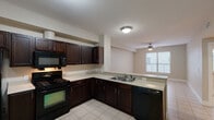 Located at 2906 E Martin Luther King Jr Blvd in Austin's 78702 zip code, this 2-bedroom, 2-bathroom unit offers a practical, single-floor layout designed for efficient everyday living. The kitchen is a standout feature, equipped with rich dark espresso cabinetry, light countertops, a full suite of black appliances including a gas range, microwave, dishwasher, and refrigerator, plus a double-basin sink. The kitchen opens directly into the living area, which is brightened by a window and fitted with a ceiling fan. Light-toned tile flooring runs consistently throughout the entire unit, lending a cohesive and easy-to-maintain aesthetic. The bedrooms are comfortably sized, each with natural light from windows and ceiling fixtures; the primary bedroom features a dedicated ceiling fan. Both bathrooms are finished with tile flooring, vanities with light countertops, and shower/tub combinations with grab bars. One bathroom also includes a built-in shelving area and washer/dryer hookups, adding practical utility. Closet storage is provided via wire-rack systems. The entry hallway includes an electrical panel and a dedicated HVAC vent, ensuring functional infrastructure throughout the home.