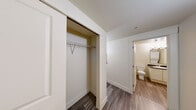 Located at 201 Yesler Way in the heart of Seattle, WA, this one-bedroom, one-bathroom residence offers a compact yet efficiently designed single-floor layout. Wood-style flooring runs throughout the unit, providing a cohesive and easy-to-maintain aesthetic across every room.

The living room is the central gathering space, featuring large black-framed windows that allow natural light to filter in and offer views of the surrounding urban streetscape. A wall-mounted HVAC unit ensures year-round climate control.

The galley-style kitchen is neatly organized with white cabinetry above and below dark countertops, providing ample storage and prep space. It is equipped with a full-size refrigerator, an electric range with coil burners, and a stainless steel sink.

The bedroom is a quiet, well-proportioned room with its own window and a sliding-door closet fitted with a hanging rod and shelf, offering practical storage. A hallway connects the bedroom to the rest of the unit and provides convenient access to the full bathroom.

The bathroom features a white vanity with a dark countertop, a large mirror with overhead lighting, and a full tub-shower combination with tiled surround. The clean, neutral color palette and wood-style flooring carry through this space as well, maintaining a consistent and tidy finish throughout the home.