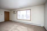 This single-floor residential unit offers a well-organized layout designed for comfortable everyday living. The living area is generously sized, featuring wall-to-wall carpet, a large picture window with blinds that fills the room with natural light and provides outdoor views, a wall-mounted air conditioning unit, and baseboard heating. A partial dividing wall separates the living area from the kitchen zone, creating a defined yet open flow between spaces.

The galley-style kitchen is efficiently laid out with warm oak cabinetry extending to the ceiling for ample storage, light-toned countertops, tile flooring, and a full suite of appliances including a refrigerator, stove, and dishwasher. A ceiling fan with light fixture adds ventilation and illumination.

Two carpeted bedrooms each feature a ceiling fan with light, a window with blinds offering exterior views, and baseboard heating, creating bright and comfortable retreats.

The unit includes two bathrooms. The first is a compact half-bath style with a pedestal sink, toilet, mirror, and tile flooring. The second is a full bathroom equipped with a tub/shower combination, toilet, and matching tile flooring. Throughout the unit, wood-toned doors and trim provide a cohesive, classic aesthetic.