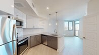 This well-appointed 1-bedroom, 1-bathroom unit offers a thoughtfully designed open-concept layout finished with light hardwood flooring throughout. The kitchen serves as the centerpiece of the living space, featuring two-tone cabinetry with white upper cabinets and dark lower cabinets, granite countertops with a subway tile backsplash, and a peninsula island with a stainless steel sink and elegant pendant lighting above. Stainless steel appliances — including a refrigerator, electric range, microwave, and dishwasher — complete the modern kitchen. The living area benefits from generous natural light through floor-to-ceiling corner windows, offering open views of the surrounding cityscape and access to a balcony. The bedroom is a calm, neutral space with light walls, hardwood flooring, and a window that continues the natural light theme. A dedicated closet provides practical storage. The bathroom is finished with clean white subway tile surrounding the tub and shower combination, granite-topped vanity, and brushed nickel fixtures, delivering a crisp, contemporary aesthetic. Throughout the unit, a consistent palette of whites and light neutrals creates a bright, cohesive, and modern living environment.