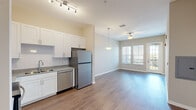 This thoughtfully laid-out one-bedroom, one-bathroom unit offers a functional and modern living experience across a single floor. The open-concept design seamlessly connects the kitchen and living area, creating an efficient and inviting shared space. The kitchen is equipped with a full suite of stainless steel appliances—including a refrigerator, electric range, built-in microwave, and dishwasher—complemented by crisp white shaker-style cabinetry, granite-look countertops, and a tile backsplash. Wood-look plank flooring runs throughout the main living areas, adding warmth and continuity to the space. The living room features a ceiling fan, a glass-paneled door, and windows fitted with horizontal blinds that allow ample natural light and outdoor views. The bedroom is carpeted for comfort, offers generous wall space, and includes closet storage along with direct access to the bathroom. The bathroom is cleanly appointed with a white vanity, granite-look countertop, mirror, and wood-look tile flooring. Neutral wall tones and clean white trim carry throughout the entire unit, creating a bright, cohesive aesthetic that provides an excellent canvas for personalization.