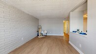 Located in Phoenix, AZ, this 2-bedroom, 2-bathroom single-story home blends classic character with modern updates. The open living room immediately draws attention with its full-length white painted brick accent wall, creating a bold yet clean focal point. Wood-look flooring runs throughout the space, adding warmth and continuity, while a textured ceiling completes the room's character.

The kitchen is thoughtfully designed with white cabinetry, white quartz-style countertops, and a full suite of stainless steel appliances including a range, microwave, dishwasher, and refrigerator. A ceiling fan with light fixture keeps the space comfortable and bright.

Both bedrooms are well-proportioned, each outfitted with ceiling fans and wood-look flooring. The primary bedroom offers a comfortable footprint with a natural light source from a window with blinds. Two closets provide ample storage throughout the home.

The bathrooms are clean and functional. One features a tub-shower combo with neutral tile, white vanity cabinetry, and warm hardware accents. The second includes a dedicated walk-in shower stall. A hallway connects the rooms efficiently, and the overall layout is practical and well-organized. This home offers a cohesive, move-in-ready aesthetic in a convenient Phoenix location.