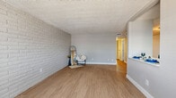 Located in Phoenix, AZ, this 2-bedroom, 2-bathroom single-story home blends classic character with modern updates. The open living room immediately draws attention with its full-length white painted brick accent wall, creating a bold yet clean focal point. Wood-look flooring runs throughout the space, adding warmth and continuity, while a textured ceiling completes the room's character.

The kitchen is thoughtfully designed with white cabinetry, white quartz-style countertops, and a full suite of stainless steel appliances including a range, microwave, dishwasher, and refrigerator. A ceiling fan with light fixture keeps the space comfortable and bright.

Both bedrooms are well-proportioned, each outfitted with ceiling fans and wood-look flooring. The primary bedroom offers a comfortable footprint with a natural light source from a window with blinds. Two closets provide ample storage throughout the home.

The bathrooms are clean and functional. One features a tub-shower combo with neutral tile, white vanity cabinetry, and warm hardware accents. The second includes a dedicated walk-in shower stall. A hallway connects the rooms efficiently, and the overall layout is practical and well-organized. This home offers a cohesive, move-in-ready aesthetic in a convenient Phoenix location.