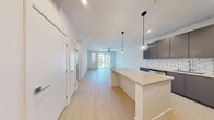 Located at 3930 Paradise Rd in Las Vegas, NV, this well-appointed one-bedroom, one-bathroom unit offers a thoughtfully designed open-concept layout across a single floor. Light wood-tone flooring flows throughout the main living areas, creating a bright and cohesive aesthetic.

The kitchen is a standout feature, showcasing sleek gray cabinetry, a striking geometric-patterned tile backsplash, quartz countertops, and a full suite of stainless steel appliances including a gas range, microwave, and refrigerator. A central island with pendant globe lighting serves as both a prep space and a natural divider between the kitchen and the expansive living area. The living room is bathed in natural light and opens directly to a private balcony through sliding glass doors, with a ceiling fan adding comfort.

The bedroom is a comfortable and well-lit retreat, featuring plush carpeting, a ceiling fan, and a generously sized window. It connects conveniently to a closet and the full bathroom, which includes a soaking tub with glass enclosure and clean white tile finishes. A hallway ties all rooms together, completing this efficiently designed and modern Las Vegas residence.