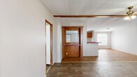 Located at 191 Railroad Street in Enigma, Georgia, this single-story home offers three bedrooms, two bathrooms, and a functional layout designed for comfortable everyday living. The living room greets you at the entry with wood-look plank flooring, neutral walls, a ceiling fan, and a front-facing window that fills the space with natural light. A pass-through with a distinctive wood-paneled surround and mirrored accent connects the living and dining areas to the kitchen, creating an open, communal feel. The galley-style kitchen is equipped with warm wood cabinetry, a dual-basin sink, a white electric range, a black refrigerator, and bold red countertops that add a pop of color. A dedicated laundry area and three closets provide ample storage throughout. The bedrooms feature the same wood-look flooring, neutral tones, and natural light from windows with blinds. The primary bedroom is generously sized and includes its own en-suite bathroom highlighted by a corner soaking tub — a notable centerpiece. The second bathroom offers a standard tub-shower combination with a vanity. The home's straightforward, single-floor plan ensures easy navigation and practicality throughout.