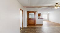 Located at 191 Railroad Street in Enigma, Georgia, this single-story home offers three bedrooms, two bathrooms, and a functional layout designed for comfortable everyday living. The living room greets you at the entry with wood-look plank flooring, neutral walls, a ceiling fan, and a front-facing window that fills the space with natural light. A pass-through with a distinctive wood-paneled surround and mirrored accent connects the living and dining areas to the kitchen, creating an open, communal feel. The galley-style kitchen is equipped with warm wood cabinetry, a dual-basin sink, a white electric range, a black refrigerator, and bold red countertops that add a pop of color. A dedicated laundry area and three closets provide ample storage throughout. The bedrooms feature the same wood-look flooring, neutral tones, and natural light from windows with blinds. The primary bedroom is generously sized and includes its own en-suite bathroom highlighted by a corner soaking tub — a notable centerpiece. The second bathroom offers a standard tub-shower combination with a vanity. The home's straightforward, single-floor plan ensures easy navigation and practicality throughout.