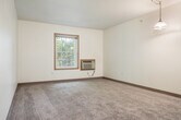 Located at 957 James St in Galena, Illinois, this single-floor, 2-bedroom, 1-bathroom residence offers a straightforward and functional layout. The interior features neutral-toned walls throughout, complemented by wall-to-wall carpeting in the living and bedroom areas that adds warmth underfoot.

The living room provides an open, versatile space with ample room for everyday living. The kitchen is equipped with a white range, refrigerator, and cabinetry with warm wood-toned finishes, alongside a breakfast bar that separates it from the living area.

Both bedrooms are carpeted and feature wood-trimmed windows that invite natural light and offer views of surrounding greenery. Each room includes wall-mounted air conditioning units for climate control. The primary bedroom is generously sized and includes a built-in closet with classic six-panel double doors, providing practical storage.

The bathroom features tile flooring in a warm stone tone, a toilet, and a sink, with accessibility-friendly grab bars near the toilet and a six-panel wood door.

Throughout the space, consistent six-panel wood doors and warm wood trim detailing contribute to a cohesive, clean aesthetic. The overall ambiance is calm and practical, well-suited for comfortable everyday living.