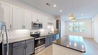 Located at 905 Lakeford Dr in Morrisville, NC, this well-appointed one-bedroom, one-bathroom residence offers a thoughtfully designed single-floor layout. The open-concept kitchen and living area serves as the heart of the home, showcasing two-tone cabinetry with crisp white upper cabinets and slate-gray lower cabinets, a herringbone-patterned tile backsplash, and a full suite of stainless steel appliances. A central island with a dark countertop provides additional prep space and casual seating, while pendant lighting adds a modern touch. Light wood-look flooring runs throughout, complementing the bright, neutral color palette.

The living area benefits from natural light through a large window, creating an inviting and airy atmosphere. The bedroom is a comfortable, well-proportioned retreat with its own window and access to a closet. The bathroom continues the modern aesthetic with gray cabinetry, a white quartz countertop, matte black hardware and fixtures, a large framed mirror, and a tiled walk-in shower with black-framed glass. Additional features include an in-unit laundry area and ample closet storage, making this a highly functional and stylish home.