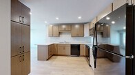 Located at 2945 Garfield Ave in Minneapolis, MN, this three-bedroom, two-bathroom unit offers a clean, modern design across a well-appointed single floor. Light hardwood flooring flows consistently throughout the space, creating a cohesive and bright aesthetic.

The kitchen is a functional centerpiece, featuring warm light wood cabinetry, light countertops with a peninsula that opens toward the living area, and a full suite of black appliances including a refrigerator, range, dishwasher, and over-range microwave. Recessed lighting and a tall pantry cabinet provide added practicality and storage.

The living room is open and airy, connected to the kitchen for a comfortable, social layout. Each of the three bedrooms is well-sized, with the primary bedroom offering generous space and large windows that bring in abundant natural light and city views. The additional bedrooms also feature wide windows with elevated views of the surrounding Minneapolis neighborhood.

Both bathrooms share a consistent, contemporary design with wood-toned floating vanities with matte black hardware, white countertops, tile flooring, and full tub-shower combinations with white subway tile surrounds. The clean, neutral palette throughout the unit lends itself to a modern and welcoming ambiance.
