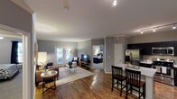 Located in Denver's dynamic Lower Downtown neighborhood, this single-floor residence at 2121 Delgany St offers a thoughtfully designed open-concept layout finished with warm hardwood-style flooring and crown molding throughout the main living areas. The kitchen is a standout feature, equipped with dark espresso cabinetry, stainless steel appliances including a refrigerator, range, and microwave, light quartz countertops, a deep sink, and a central island with bar seating — ideal for both cooking and casual dining. The living room is generously sized, featuring large French doors that open to a private balcony, filling the space with natural light. Two well-proportioned bedrooms provide comfortable retreats; the primary bedroom includes plush carpeting, a ceiling fan, and a natural window view, while the second bedroom also features carpeted floors and a ceiling fan. Each bathroom is finished with wood-style flooring, a tub-shower combination, and a dark-toned vanity with a white countertop. One bathroom offers walk-in closet access, adding practical storage. The neutral gray wall palette and clean architectural details create a cohesive, modern ambiance throughout this well-appointed Denver residence.